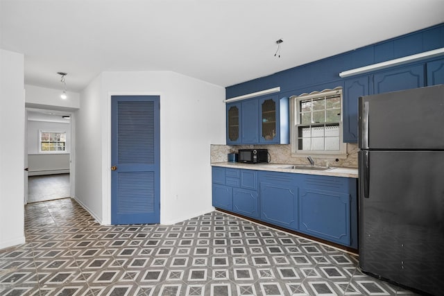 125 Lakewood Dr, Congers, NY 10920 - kitchen with freestanding refrigerator, blue cabinetry, light countertops, glass insert cabinets, and decorative backsplash