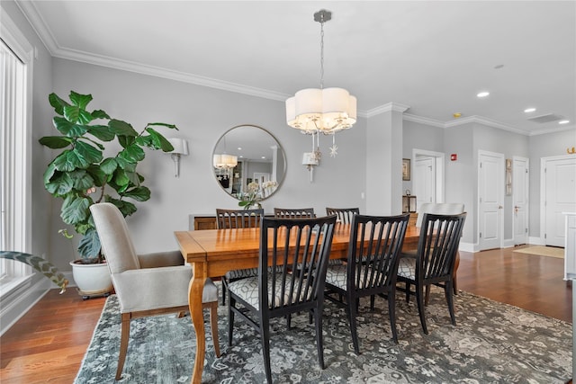 dining space with ornamental molding, wood finished floors, and a chandelier