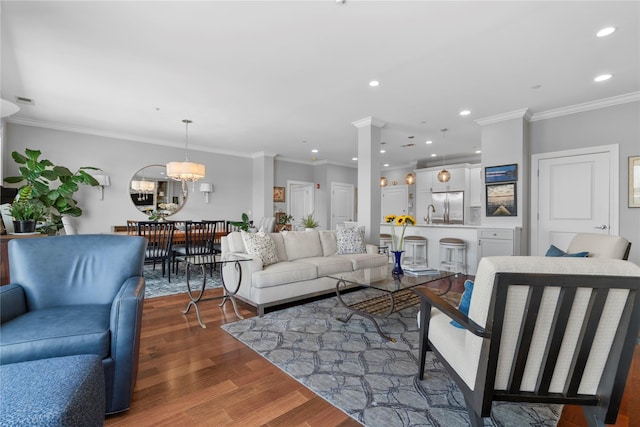living area featuring crown molding, recessed lighting, an inviting chandelier, and wood finished floors