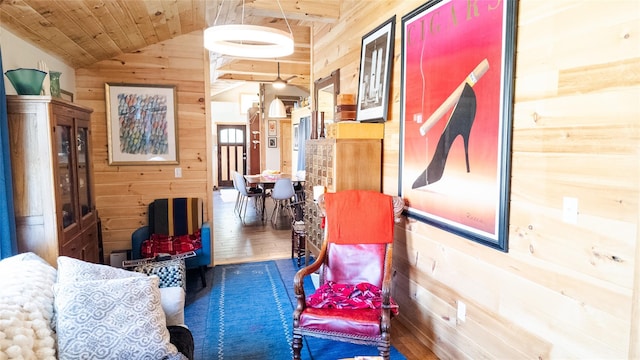 sitting room with vaulted ceiling, wooden ceiling, wood walls, and wood finished floors
