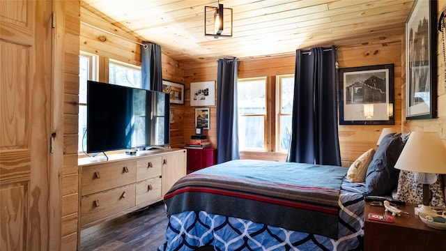 bedroom featuring wood walls, dark wood-style flooring, and multiple windows
