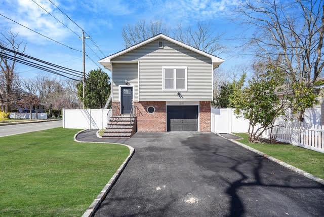 view of front of house featuring brick siding, a front lawn, driveway, and fence