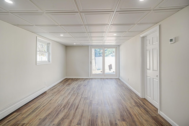 unfurnished room featuring a baseboard radiator, wood finished floors, and baseboards