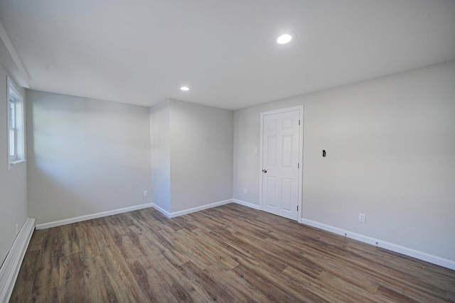 empty room with baseboards, wood finished floors, baseboard heating, and recessed lighting