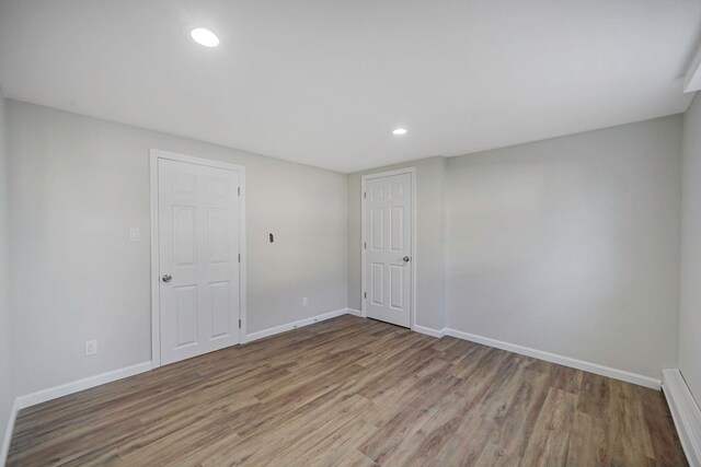 empty room featuring baseboards, wood finished floors, and recessed lighting