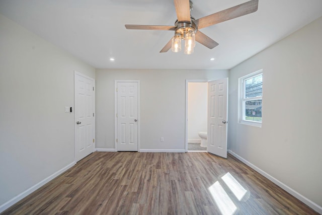 unfurnished bedroom featuring recessed lighting, wood finished floors, ensuite bath, and baseboards