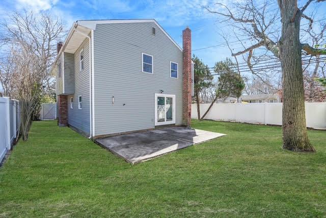 back of house featuring a yard, a patio area, a chimney, and a fenced backyard
