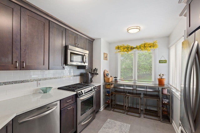 kitchen featuring appliances with stainless steel finishes, plenty of natural light, backsplash, and dark brown cabinets