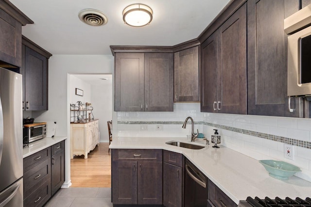 kitchen featuring visible vents, a sink, appliances with stainless steel finishes, and dark brown cabinetry