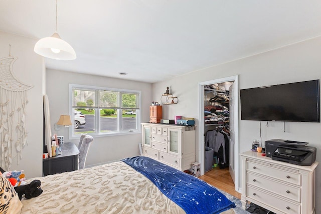 bedroom with a closet, light wood-style flooring, and a walk in closet