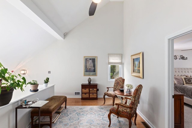 living area with beam ceiling, a ceiling fan, baseboards, wood finished floors, and visible vents