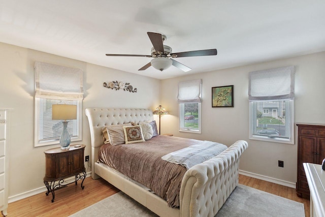 bedroom featuring baseboards, multiple windows, ceiling fan, and light wood-type flooring