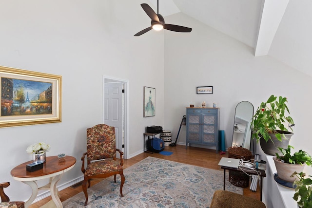 living area with high vaulted ceiling, ceiling fan, and wood finished floors