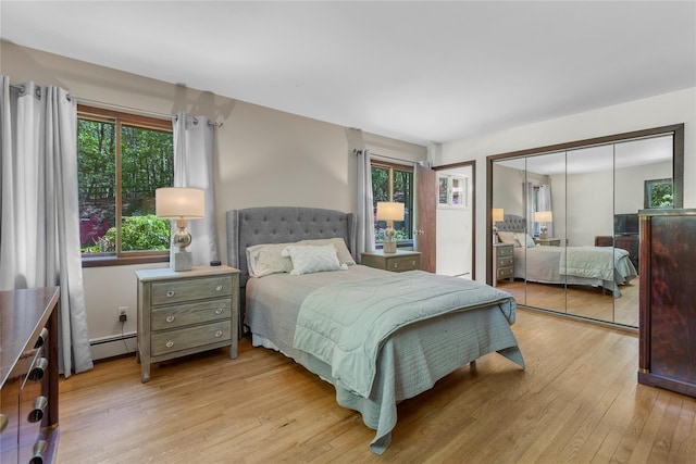 9 Salonga Woods Rd, Northport, NY 11768 - bedroom with light wood-style floors, multiple windows, baseboard heating, and a closet