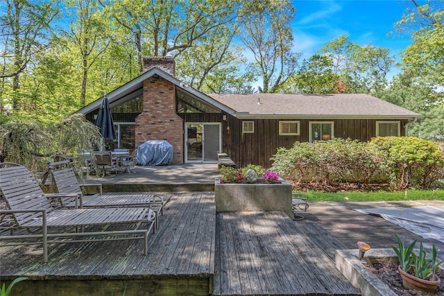 9 Salonga Woods Rd, Northport, NY 11768 - back of property featuring a wooden deck, a chimney, outdoor dining space, and board and batten siding