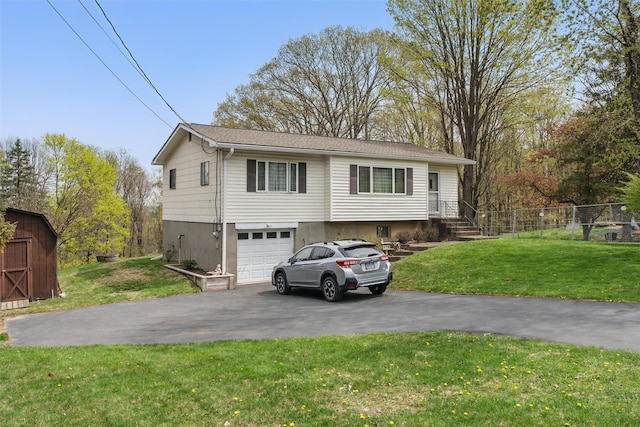 view of front of property featuring a garage, fence, a front lawn, and aphalt driveway