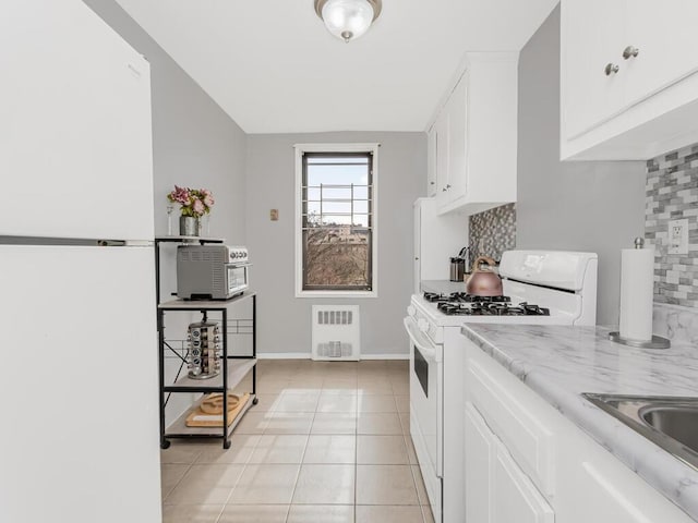 270 N Broadway Unit 6H, Yonkers, NY 10701 - kitchen featuring tasteful backsplash, radiator, white cabinetry, white appliances, and light tile patterned floors