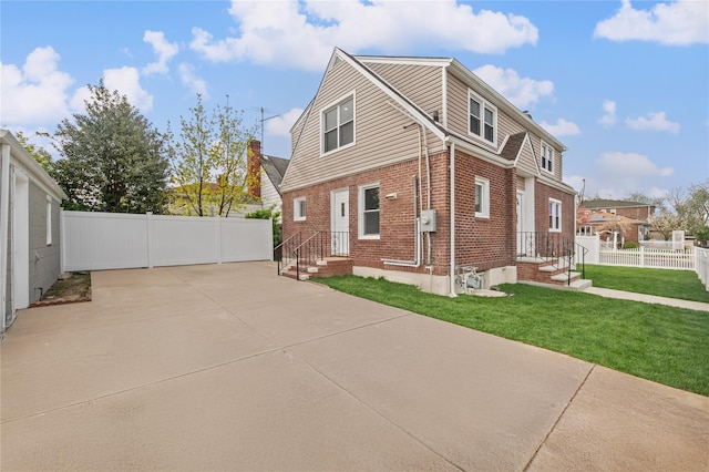 exterior space featuring brick siding, fence, and a lawn
