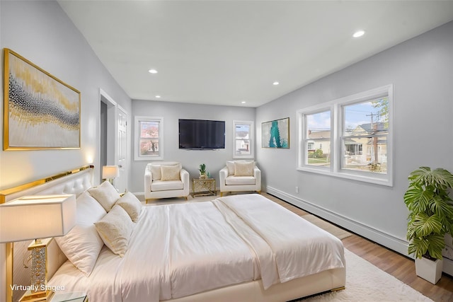 bedroom with recessed lighting, wood finished floors, multiple windows, and a baseboard radiator