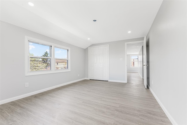unfurnished bedroom with lofted ceiling, light wood-style flooring, a closet, baseboards, and recessed lighting