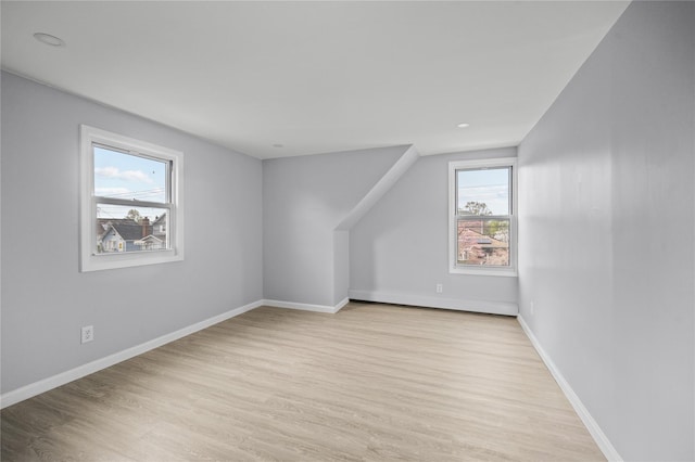 additional living space with baseboards and light wood-type flooring
