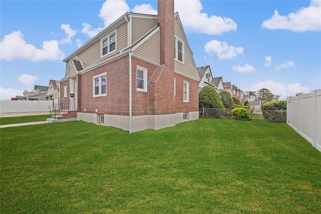 view of side of property with a residential view, a yard, a chimney, a fenced backyard, and brick siding