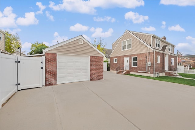 view of property exterior featuring brick siding, driveway, a garage, and a gate