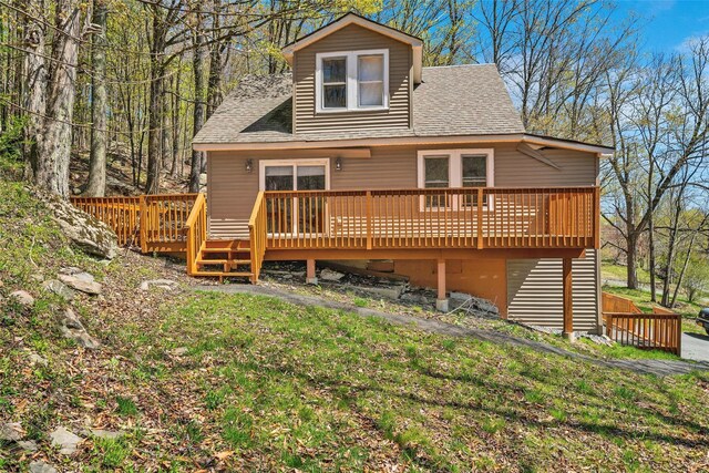 rear view of property with a lawn, a shingled roof, and a wooden deck