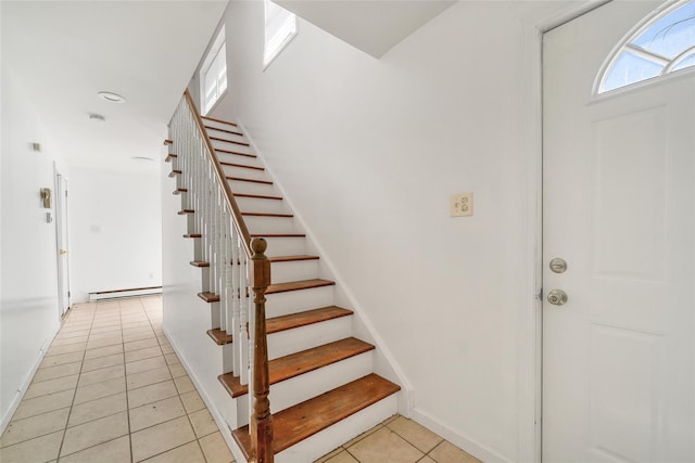 entryway with light tile patterned flooring, baseboards, baseboard heating, and stairway