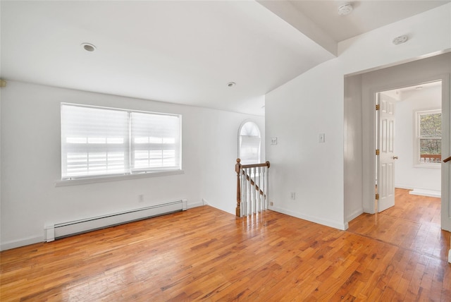 spare room featuring baseboards, a baseboard heating unit, and light wood-style flooring