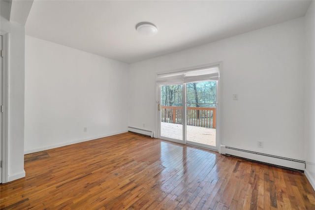 spare room with baseboards, hardwood / wood-style floors, and a baseboard radiator