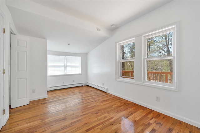 empty room with baseboard heating, baseboards, lofted ceiling, light wood-type flooring, and a baseboard heating unit