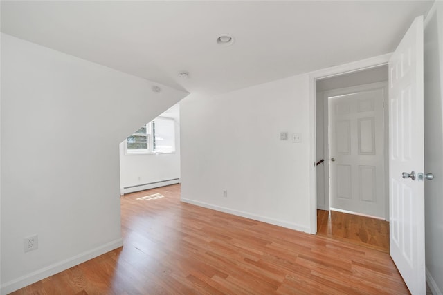 additional living space featuring light wood-style floors, baseboards, and a baseboard heating unit