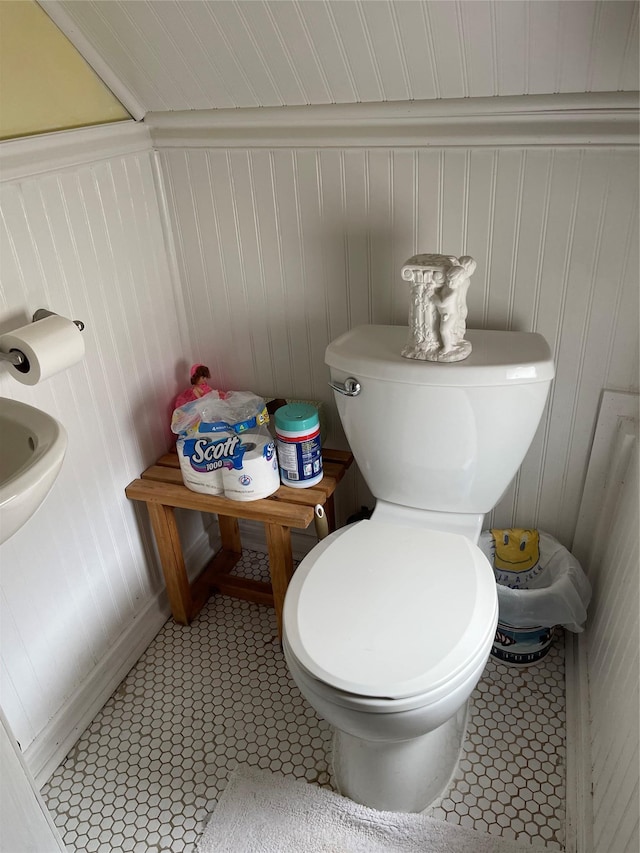 20815 38th Ave, Bayside, NY 11361 - half bath featuring toilet, tile patterned flooring, wooden walls, and a decorative wall