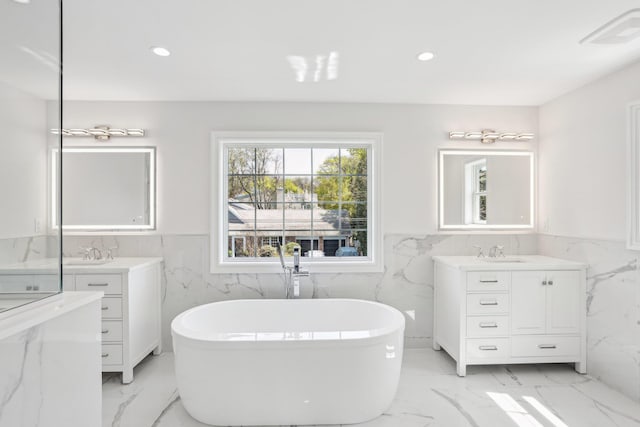 44 Harbor Hills Dr, Port Washington, NY 11050 - bathroom featuring a soaking tub, a sink, tile walls, marble finish floor, and wainscoting