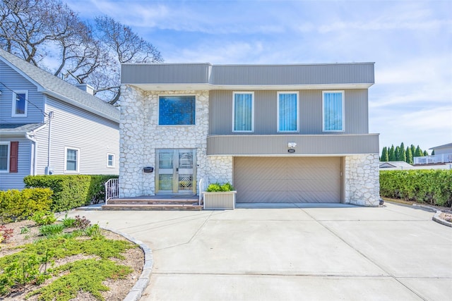 contemporary house with a garage, driveway, and stone siding