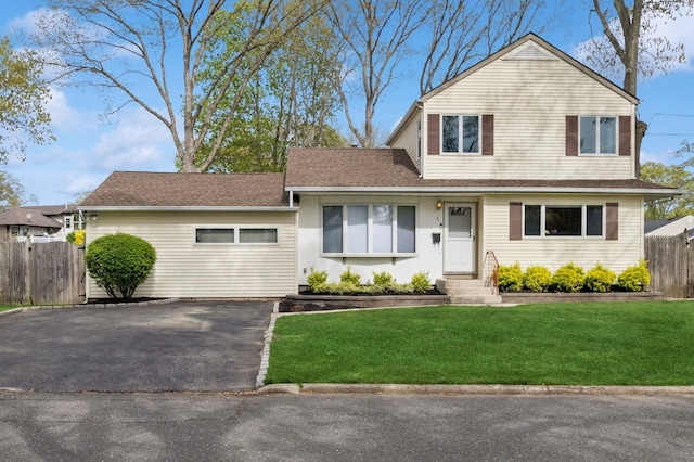 view of front of home with aphalt driveway, fence, a front yard, and entry steps