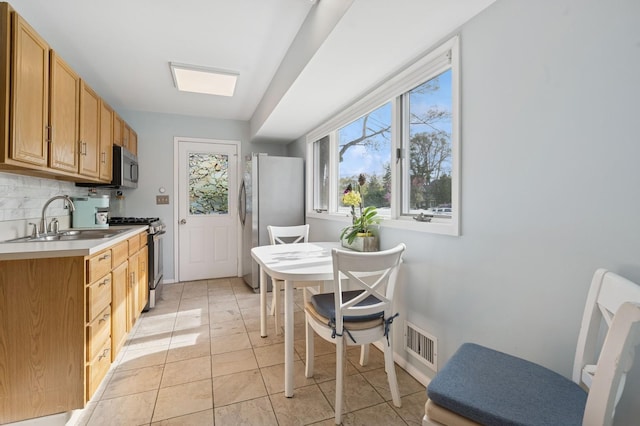kitchen with visible vents, light tile patterned flooring, light countertops, a sink, and appliances with stainless steel finishes