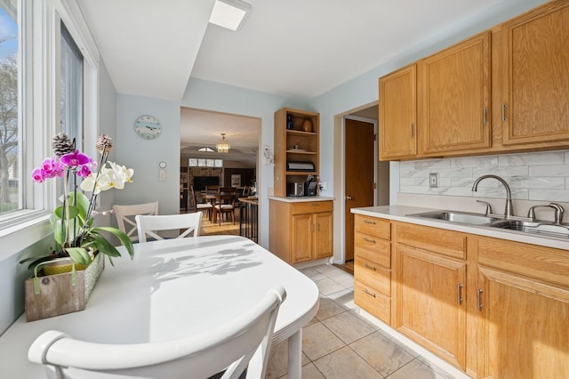 kitchen with a sink, light countertops, backsplash, and a healthy amount of sunlight