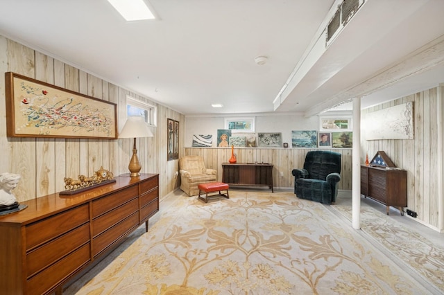 sitting room with wooden walls, light colored carpet, and visible vents