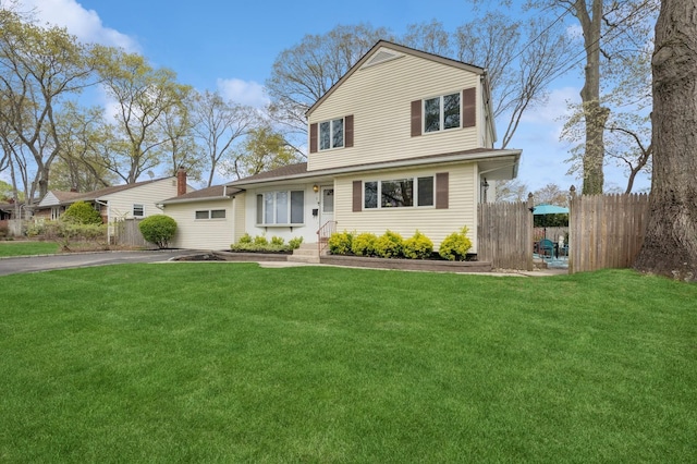 traditional-style home with fence, a front lawn, and aphalt driveway