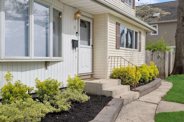 view of exterior entry with fence and board and batten siding