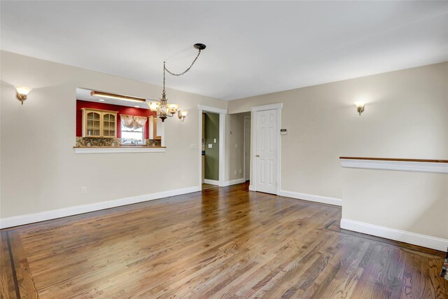 interior space with wood finished floors, baseboards, and a notable chandelier