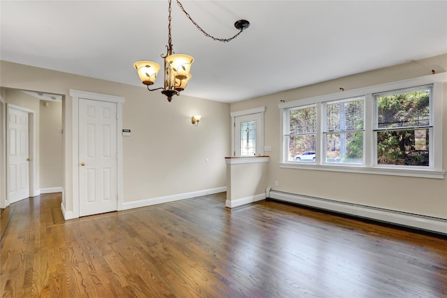 spare room featuring baseboards, baseboard heating, wood finished floors, and a chandelier