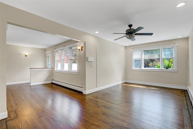spare room featuring baseboard heating, wood finished floors, and a wealth of natural light