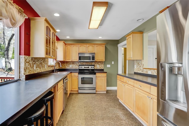 kitchen featuring light brown cabinets, appliances with stainless steel finishes, a sink, and dark countertops