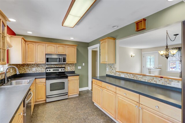 kitchen featuring dark countertops, appliances with stainless steel finishes, a sink, and light brown cabinetry
