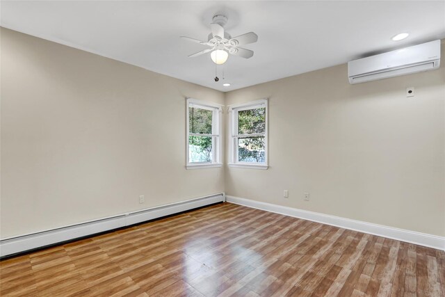 spare room with a baseboard heating unit, light wood-style flooring, baseboards, a wall mounted air conditioner, and ceiling fan