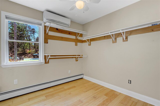 walk in closet featuring ceiling fan, wood finished floors, an AC wall unit, and a baseboard radiator