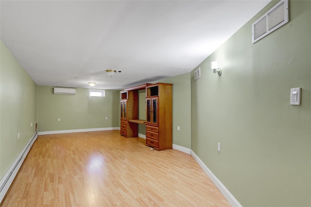 interior space with visible vents, a wall unit AC, light wood-style floors, and a baseboard radiator